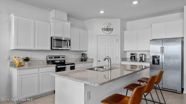 kitchen featuring sink, white cabinetry, a center island with sink, appliances with stainless steel finishes, and light stone countertops