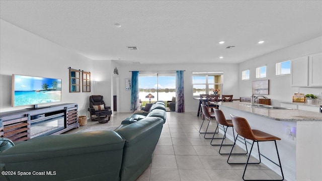 living room with sink, light tile patterned floors, and a textured ceiling