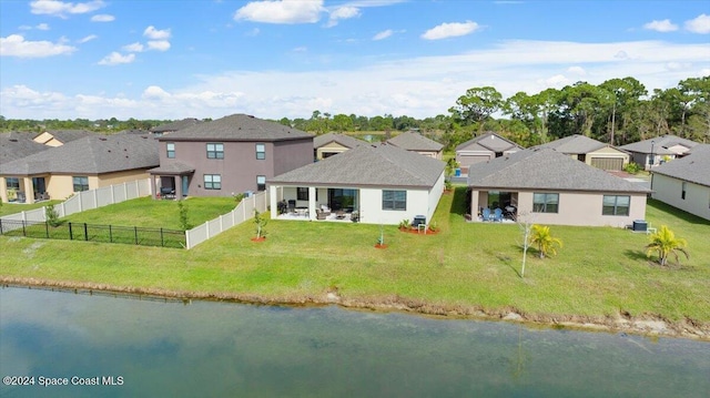 rear view of house featuring a water view and a yard