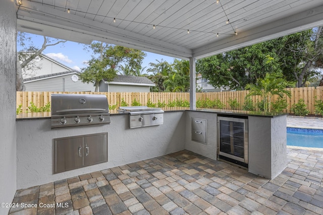 view of patio / terrace featuring wine cooler, a fenced in pool, and area for grilling