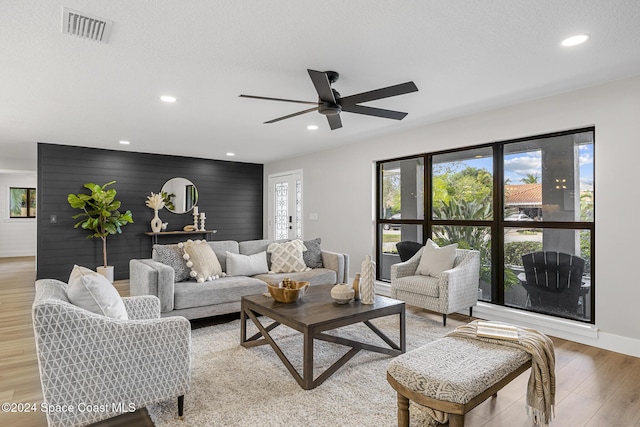 living room with ceiling fan, light hardwood / wood-style flooring, and a textured ceiling