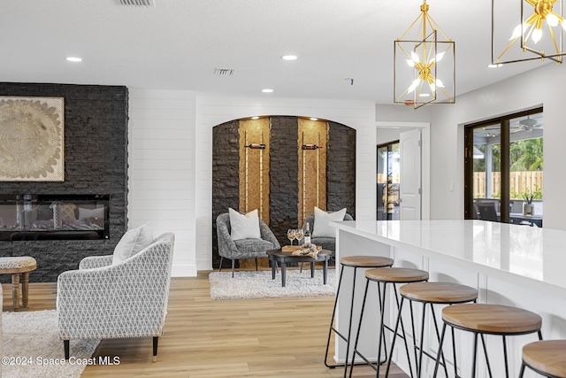 interior space featuring pendant lighting, an inviting chandelier, a kitchen breakfast bar, light wood-type flooring, and a fireplace