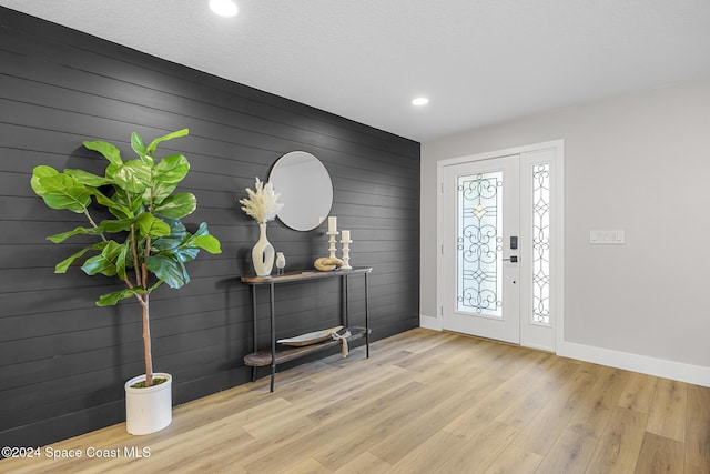 entrance foyer with light wood-type flooring and wooden walls