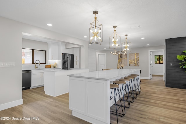 kitchen featuring appliances with stainless steel finishes, light wood-type flooring, white cabinetry, and a kitchen island