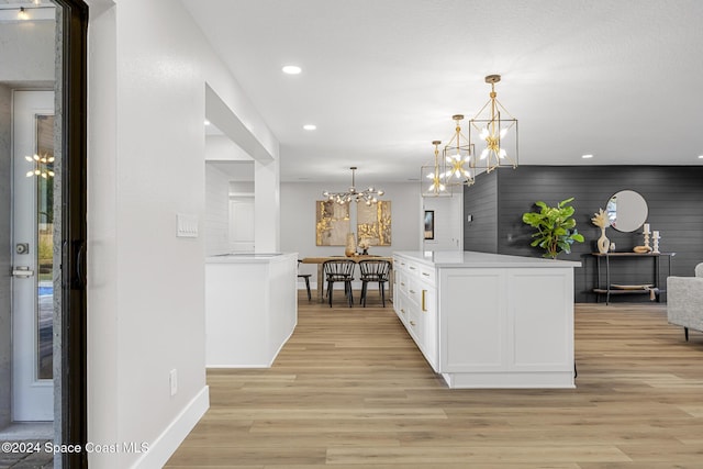 kitchen with pendant lighting, a notable chandelier, white cabinetry, and light hardwood / wood-style flooring