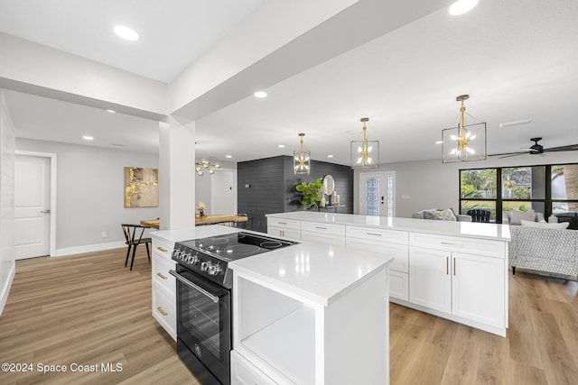 kitchen with a center island, black electric range oven, white cabinets, light wood-type flooring, and decorative light fixtures