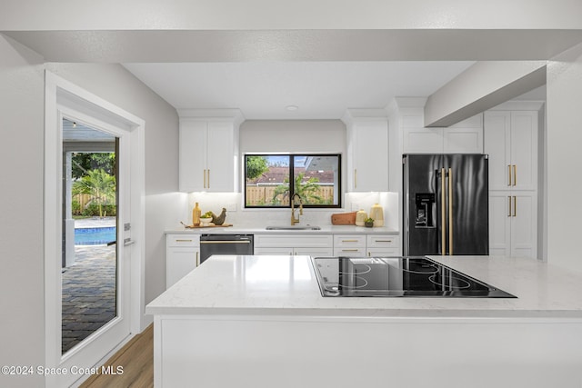 kitchen featuring white cabinets, light stone counters, sink, and appliances with stainless steel finishes