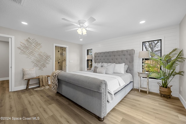 bedroom featuring hardwood / wood-style floors, a textured ceiling, ensuite bathroom, and ceiling fan