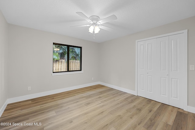 unfurnished bedroom with a closet, ceiling fan, light hardwood / wood-style flooring, and a textured ceiling