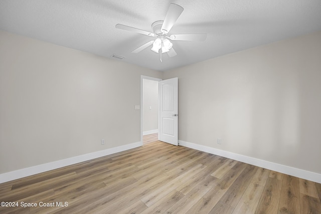 empty room featuring ceiling fan, light wood-type flooring, and a textured ceiling