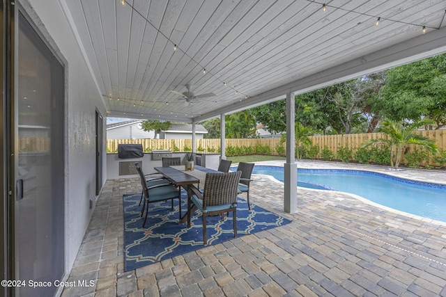 view of swimming pool with a patio, ceiling fan, and exterior kitchen