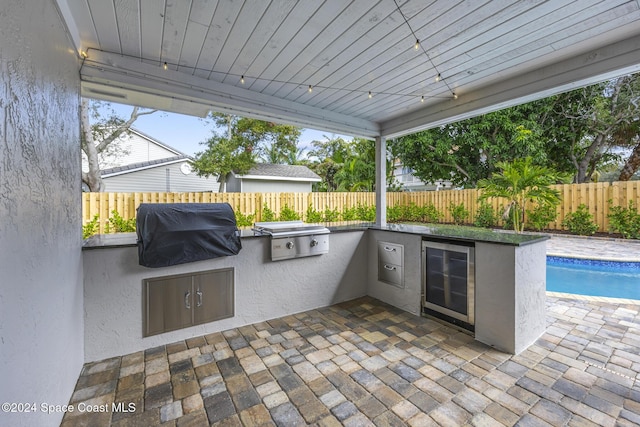 view of patio / terrace featuring a fenced in pool, grilling area, exterior kitchen, and wine cooler