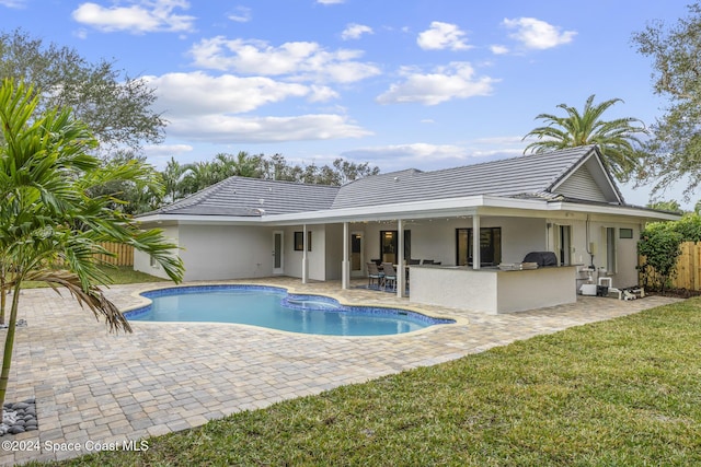 view of swimming pool featuring exterior bar, a yard, a patio, and area for grilling