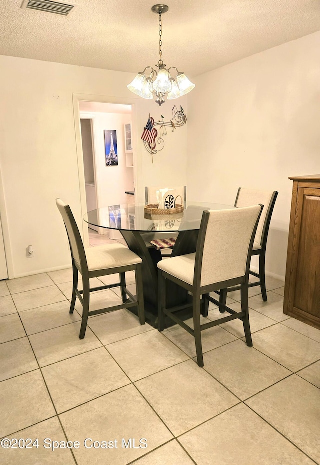 tiled dining space with a chandelier and a textured ceiling