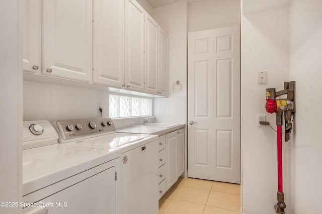 clothes washing area featuring light tile patterned flooring, cabinets, independent washer and dryer, and sink