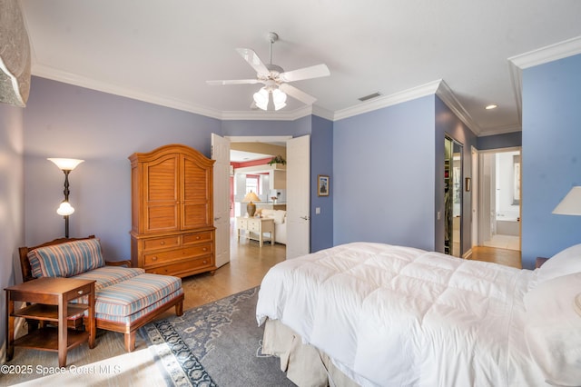 bedroom featuring hardwood / wood-style flooring, ensuite bath, ceiling fan, and crown molding