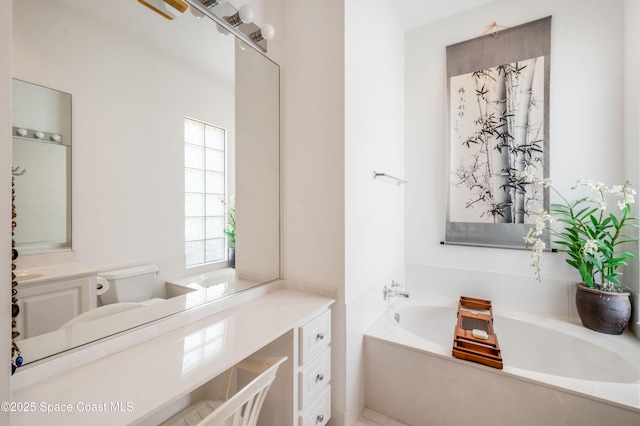 bathroom featuring a washtub, vanity, and toilet