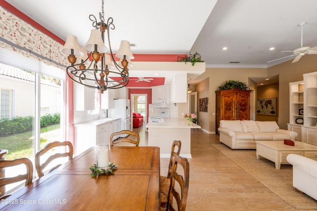 dining room with ceiling fan with notable chandelier, light hardwood / wood-style floors, crown molding, and sink