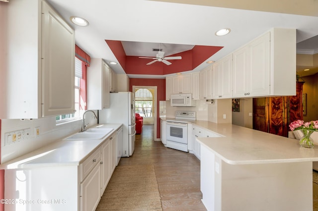 kitchen featuring white appliances, sink, kitchen peninsula, ceiling fan, and white cabinetry