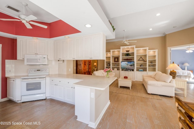 kitchen with kitchen peninsula, white appliances, crown molding, white cabinets, and light hardwood / wood-style floors