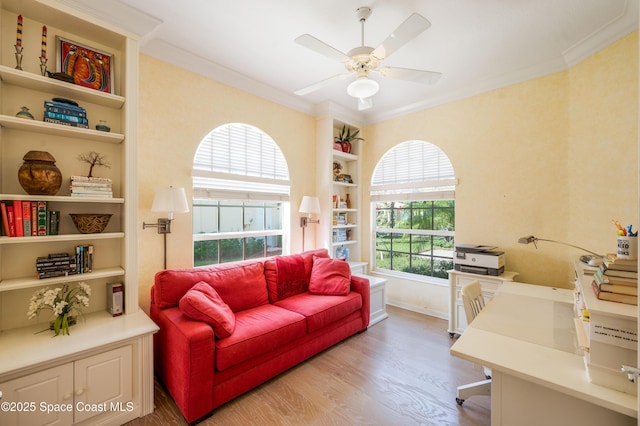 office space featuring light hardwood / wood-style floors, built in features, ceiling fan, and crown molding