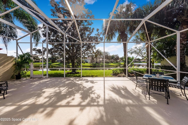 view of patio featuring glass enclosure and a water view