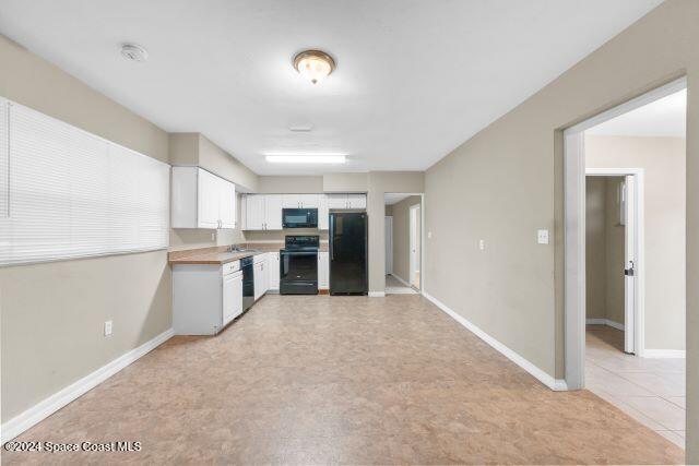 kitchen with white cabinets, light tile patterned floors, and black appliances