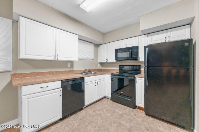 kitchen with black appliances, white cabinetry, and sink