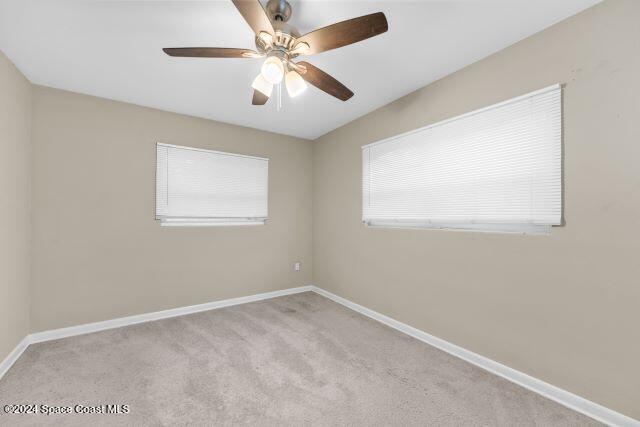 empty room featuring light carpet, ceiling fan, and a healthy amount of sunlight