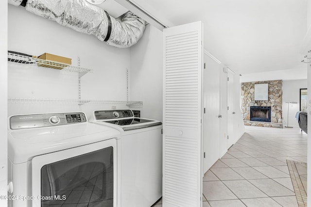 laundry room featuring independent washer and dryer, light tile patterned floors, and a stone fireplace