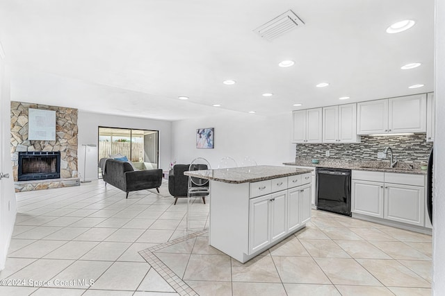 kitchen featuring a fireplace, white cabinetry, dishwasher, and sink