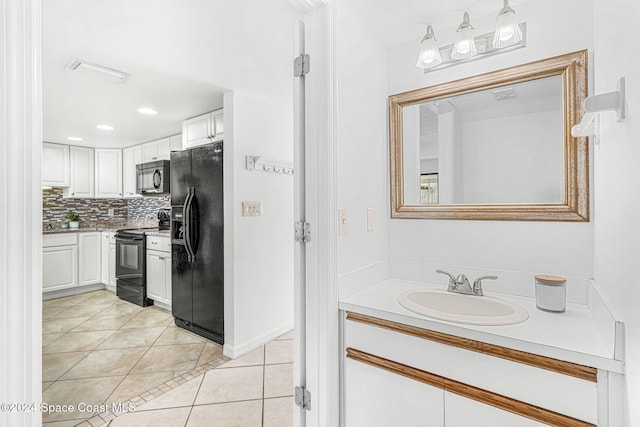 kitchen featuring light tile patterned flooring, sink, white cabinets, and black appliances