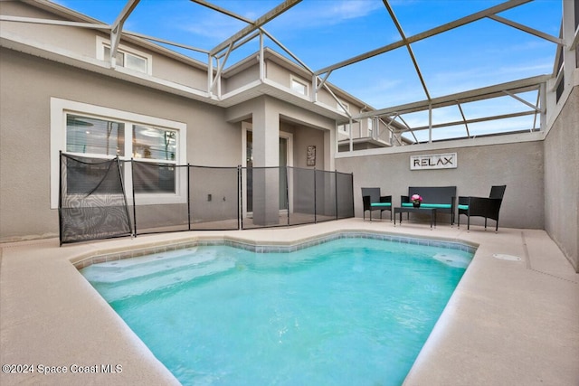 view of swimming pool with an outdoor living space, a patio, and a lanai