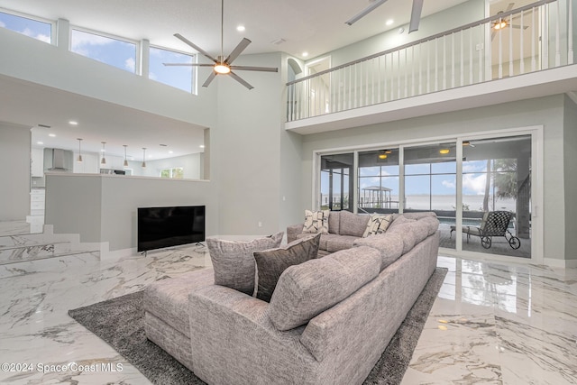 living room featuring ceiling fan, plenty of natural light, and a high ceiling