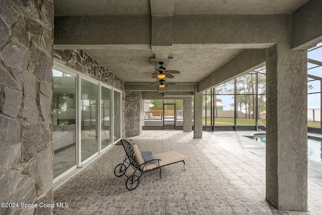 unfurnished sunroom with ceiling fan and a swimming pool