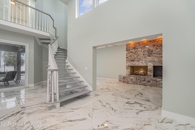 stairway with a towering ceiling and a stone fireplace