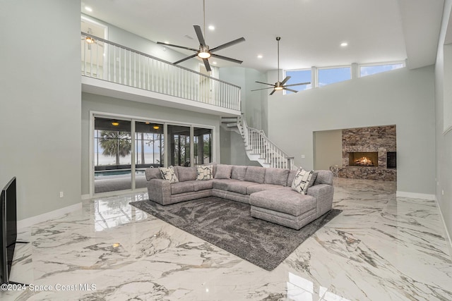 living room featuring a fireplace, a high ceiling, and ceiling fan