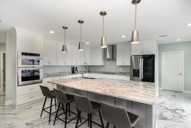 kitchen featuring appliances with stainless steel finishes, sink, wall chimney range hood, decorative light fixtures, and a large island