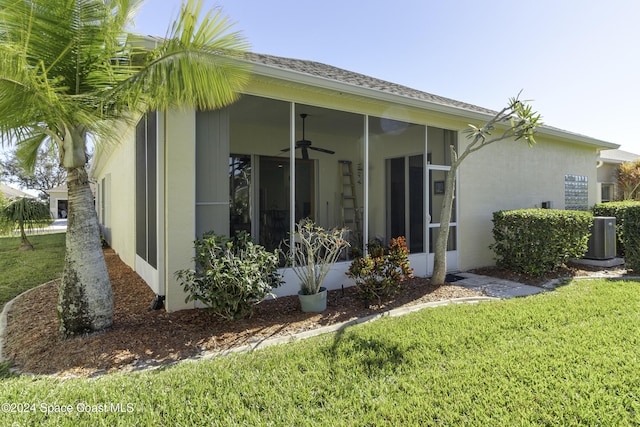 view of side of property with a lawn, ceiling fan, central air condition unit, and a sunroom