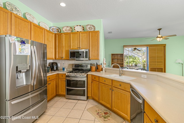 kitchen featuring ceiling fan, sink, stainless steel appliances, decorative backsplash, and light tile patterned flooring