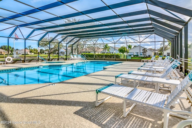 view of pool featuring glass enclosure and a patio