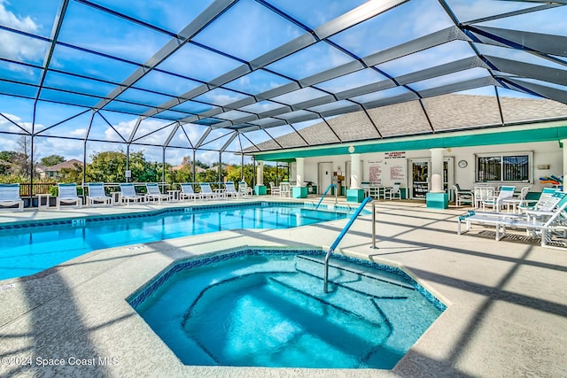 view of swimming pool featuring glass enclosure, an in ground hot tub, and a patio area