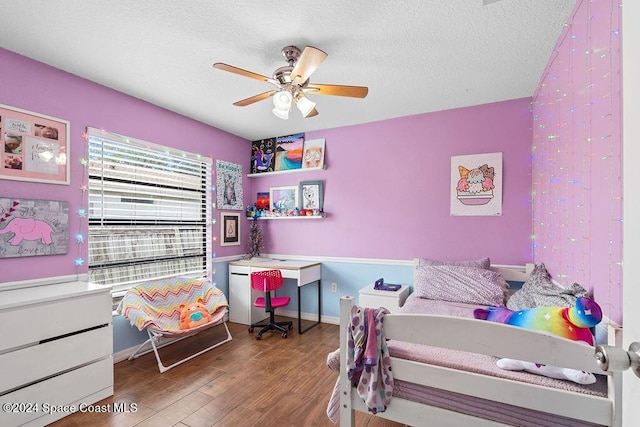 bedroom with ceiling fan, hardwood / wood-style floors, and a textured ceiling