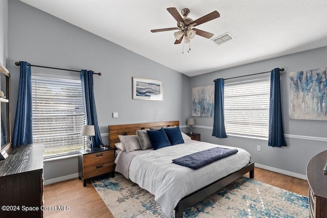 bedroom with multiple windows, vaulted ceiling, light hardwood / wood-style flooring, and ceiling fan