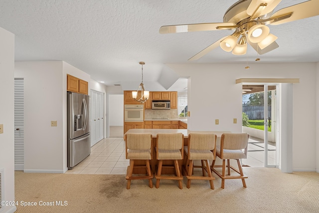 kitchen with stainless steel appliances, tasteful backsplash, decorative light fixtures, light carpet, and a breakfast bar