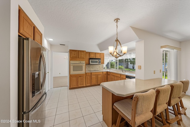 kitchen featuring pendant lighting, a breakfast bar area, a notable chandelier, kitchen peninsula, and stainless steel appliances