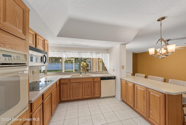 kitchen with pendant lighting, white appliances, sink, kitchen peninsula, and a breakfast bar area