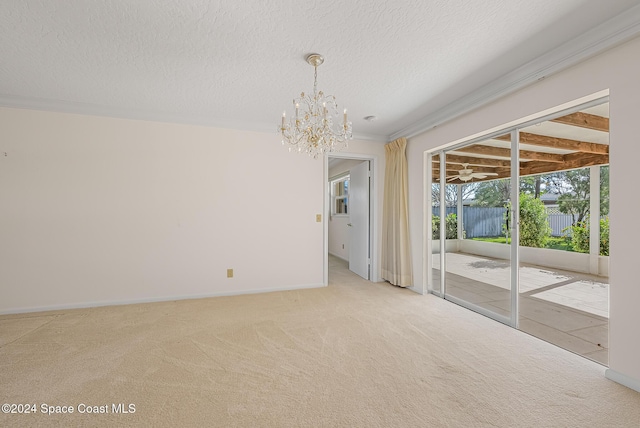 spare room featuring carpet flooring, a textured ceiling, an inviting chandelier, and crown molding