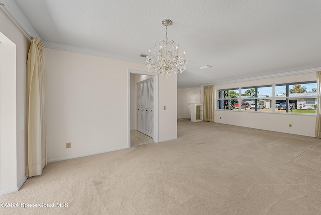 unfurnished living room with a textured ceiling, light colored carpet, crown molding, and a notable chandelier