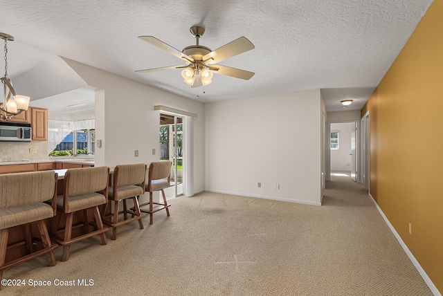 carpeted living room with a textured ceiling, ceiling fan, and a healthy amount of sunlight